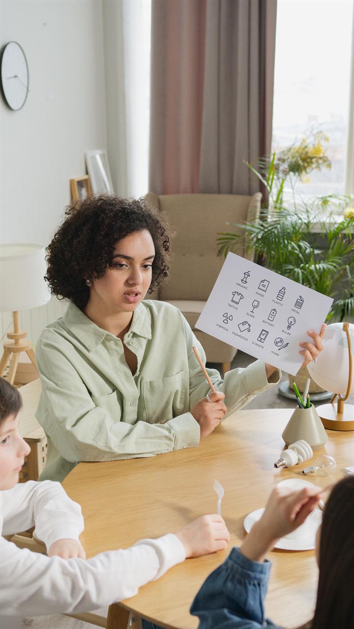 A special education professional using a picture communication chart to work with two young students at a table